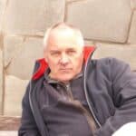 Padraig Rooney reclining on one arm in front of a stone wall.
