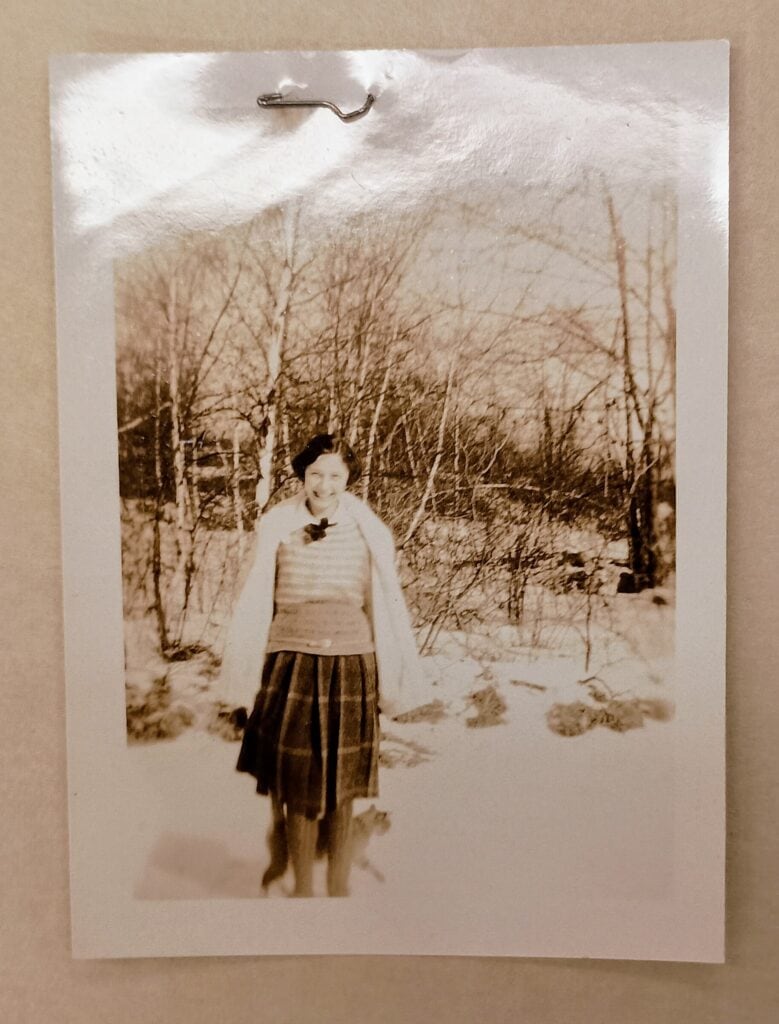 Geneva Jensen standing and smiling in front of a wooded hill